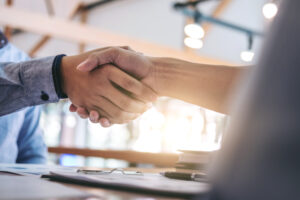 two smiling businessman shaking hands together after good deal c